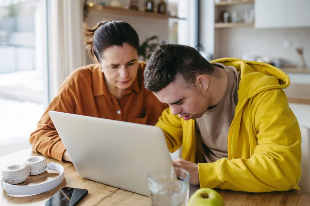 Disabled man and support worker looking at laptop