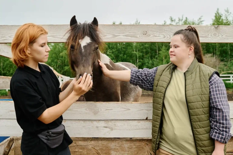Disabled woman with support worker patting horse